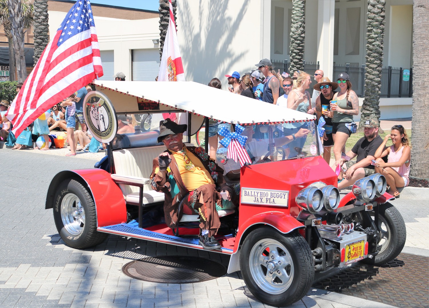An elaborately costumed man sits in the front seat of one of the Shriners Hospitals for Children’s many cars in the parade.